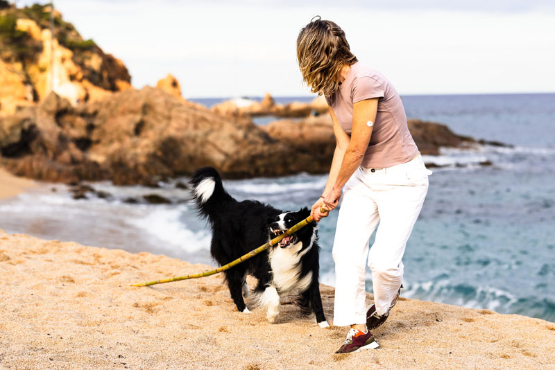 Woman on Beach playing with her dog wearing a CGM